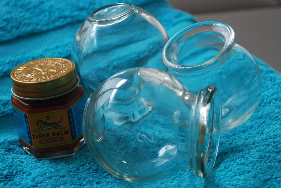 Ventouses en verre et pot de baume posés sur une serviette turquoise